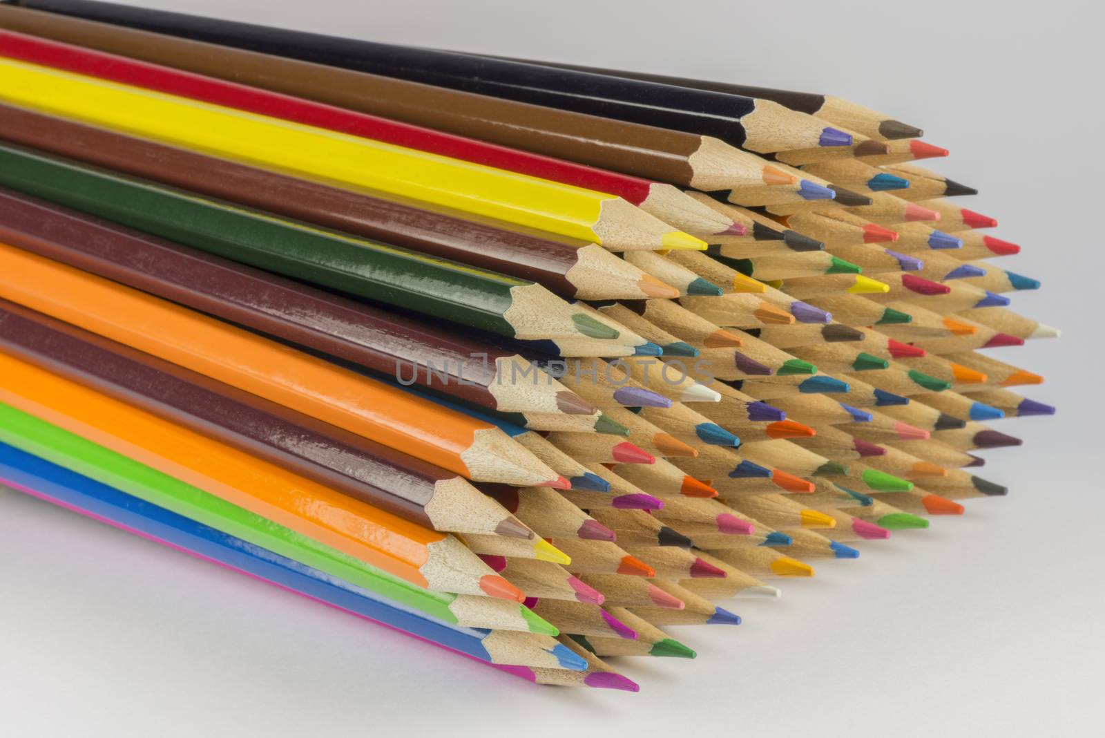 Abstract composition of a set wooden colour pencils against a white background
