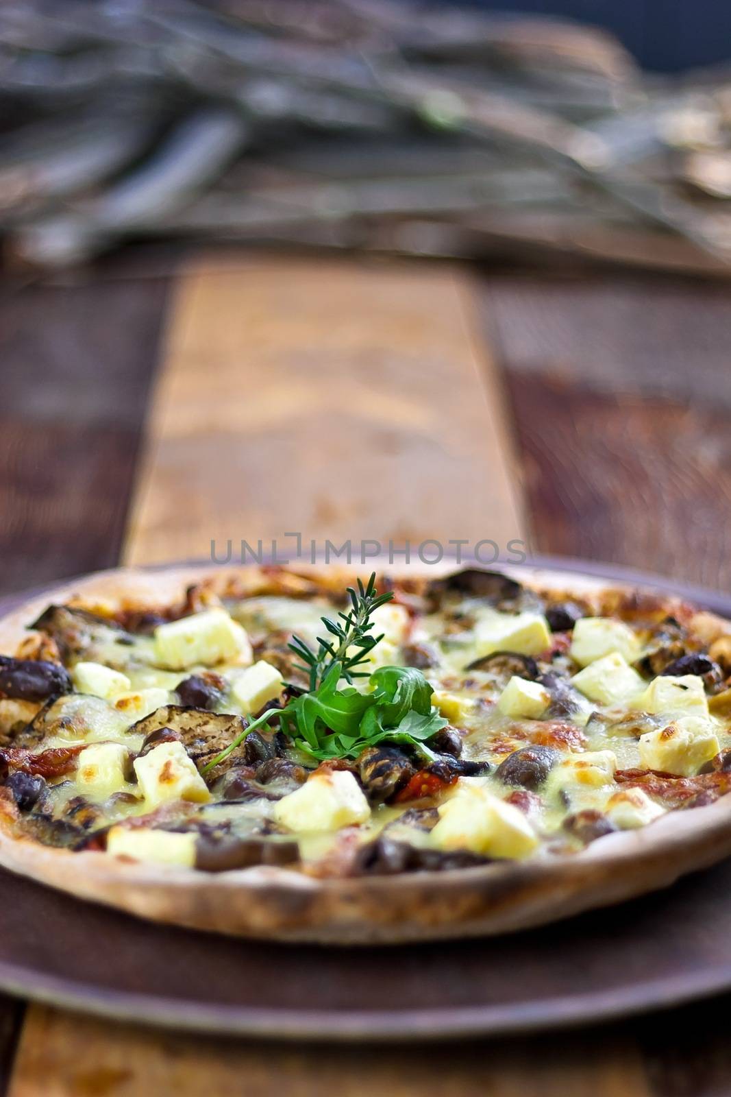 A Rustic Vegetarian pizza laid out on a wooden tray on a wooden table in a pizzeria.