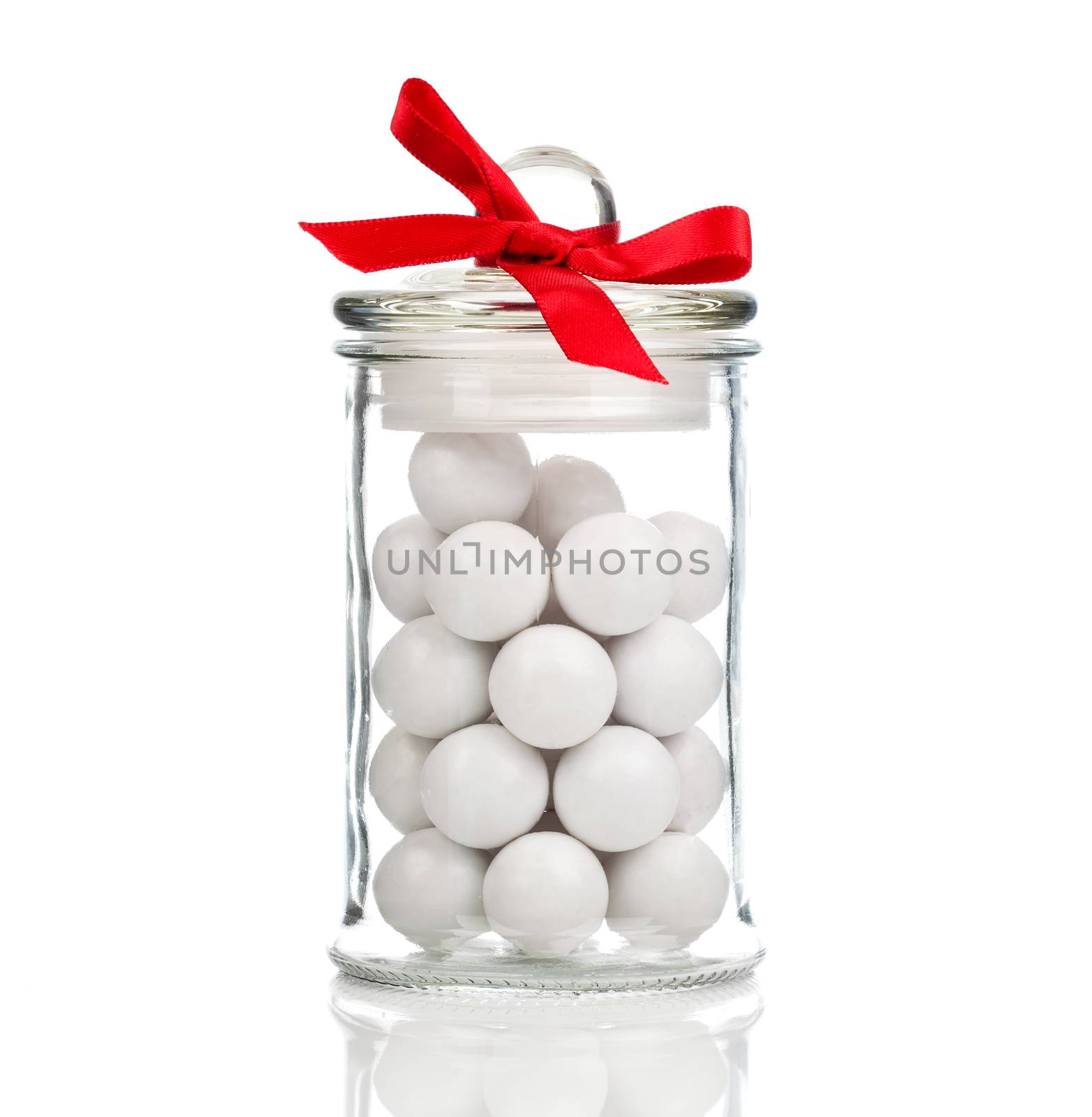 white candies, Gumballs in glass jar, over white background by motorolka