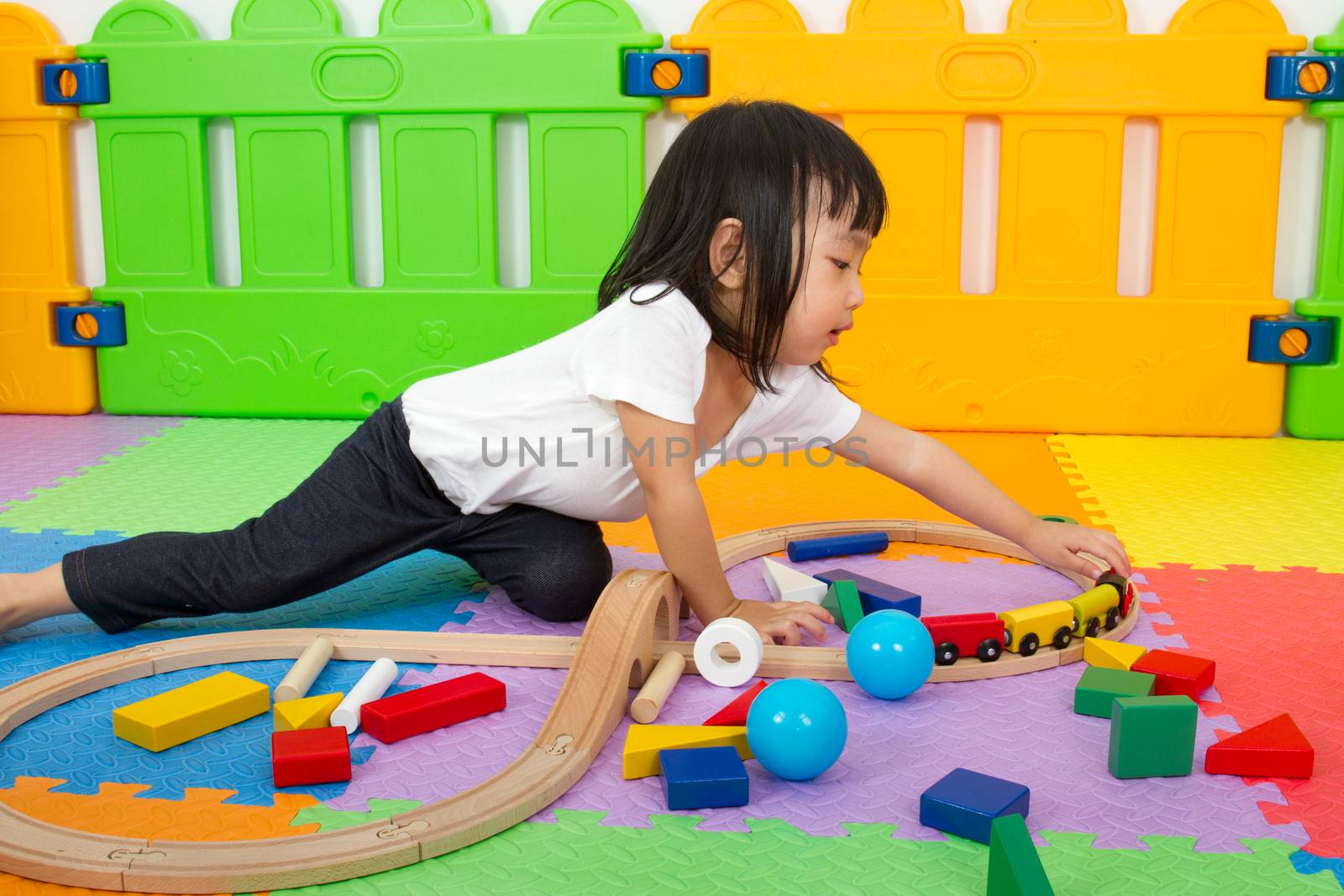 Asian Chinese little girl playing with blocks and toys train on the floor at kingdergarten.