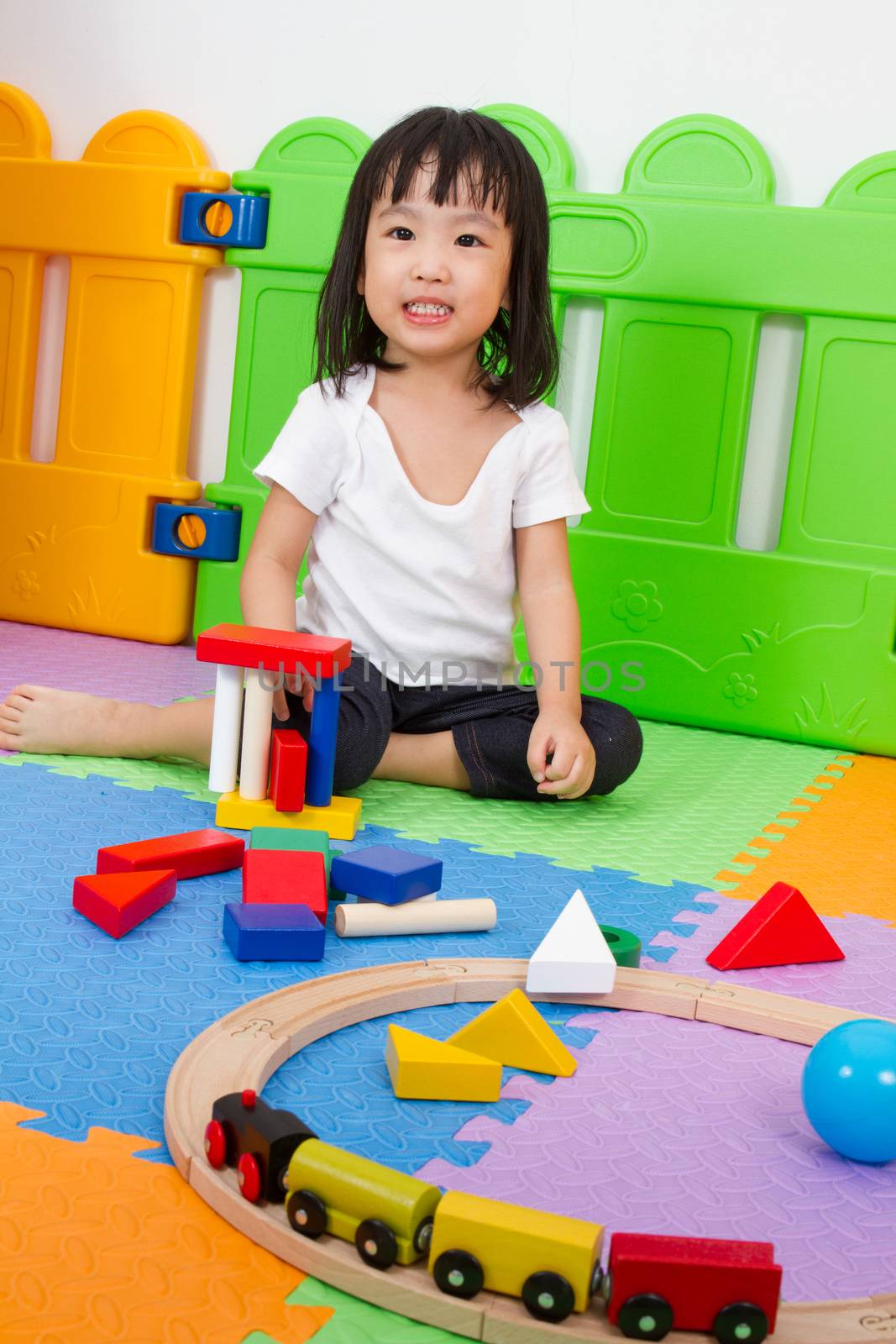 Asian Chinese little girl playing with blocks and toys train on the floor at kingdergarten.