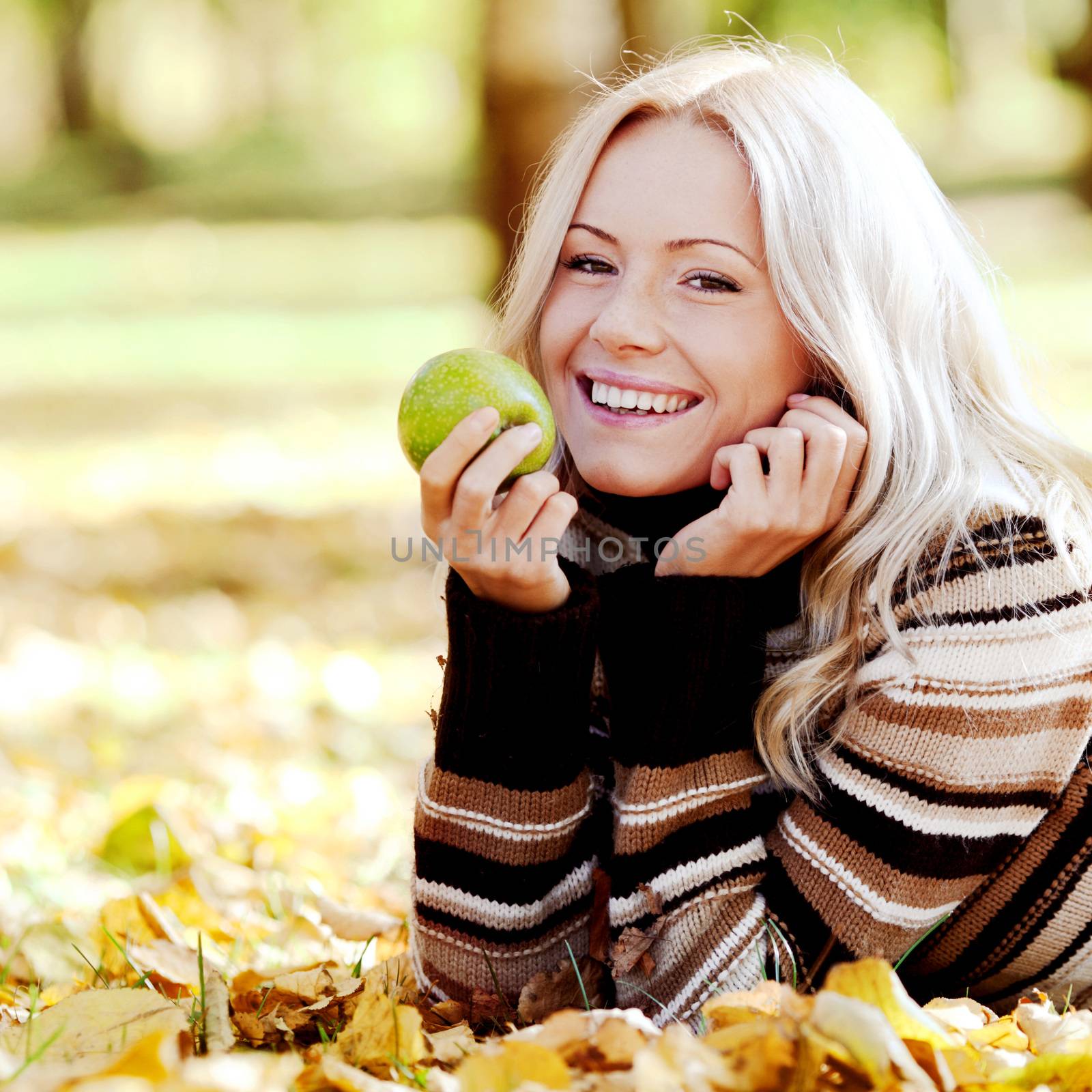 Beautiful woman with green apple in autumn park