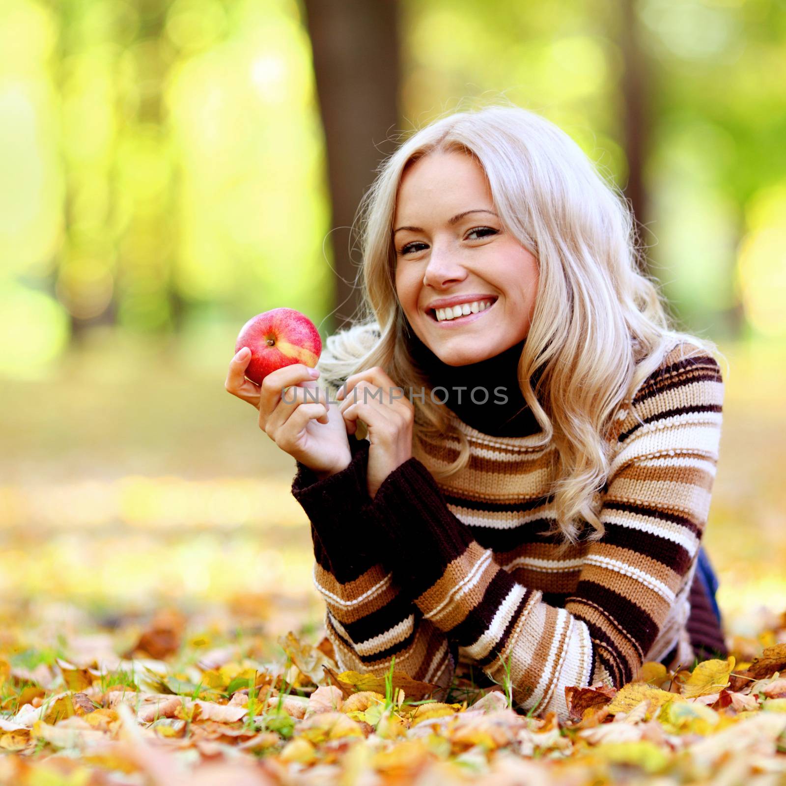 Beautiful woman with red apple in autumn park