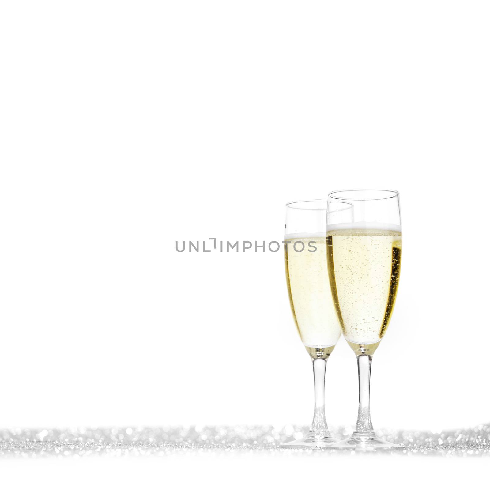 Glasses of champagne on silver glitters isolated on white