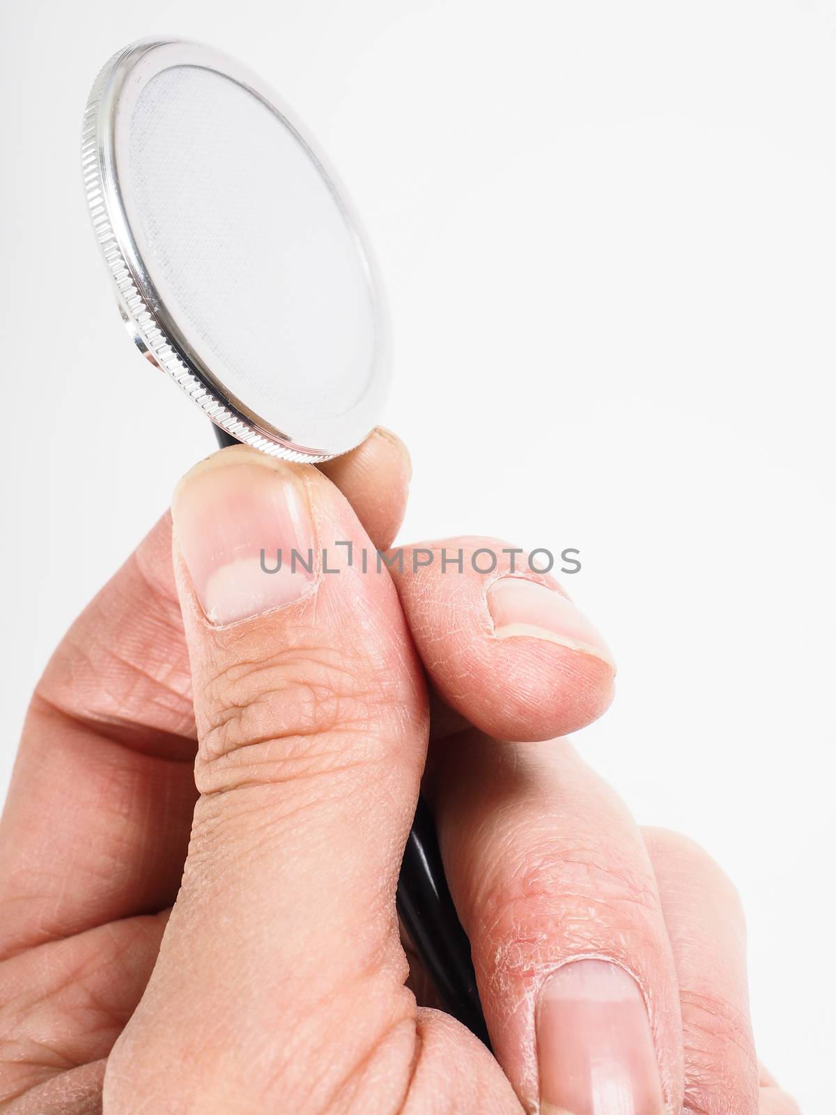 Closeup of hand holding a stethoscope towards bright background by Arvebettum