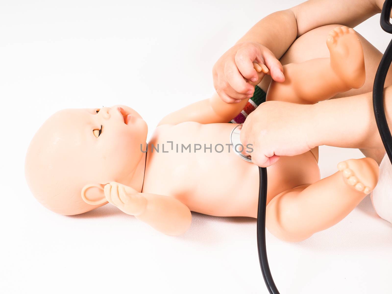 Toddler running a health check on a hairless doll with a stethoscope