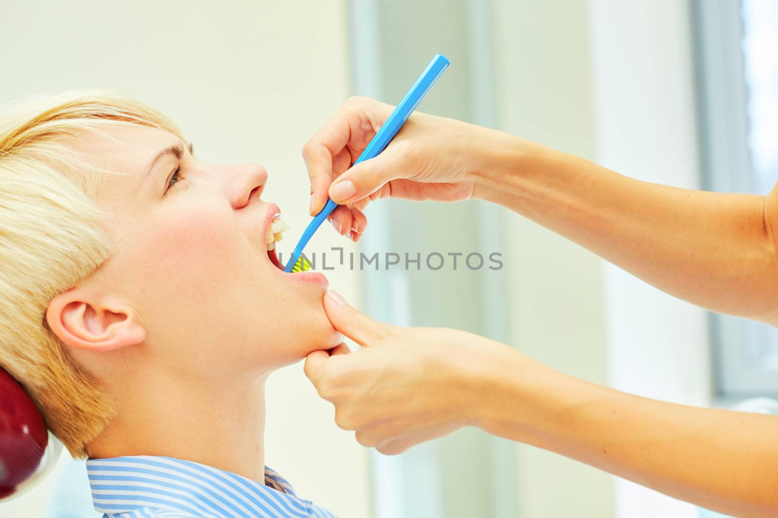 dentist brushing teeth to her patient in dental clinic