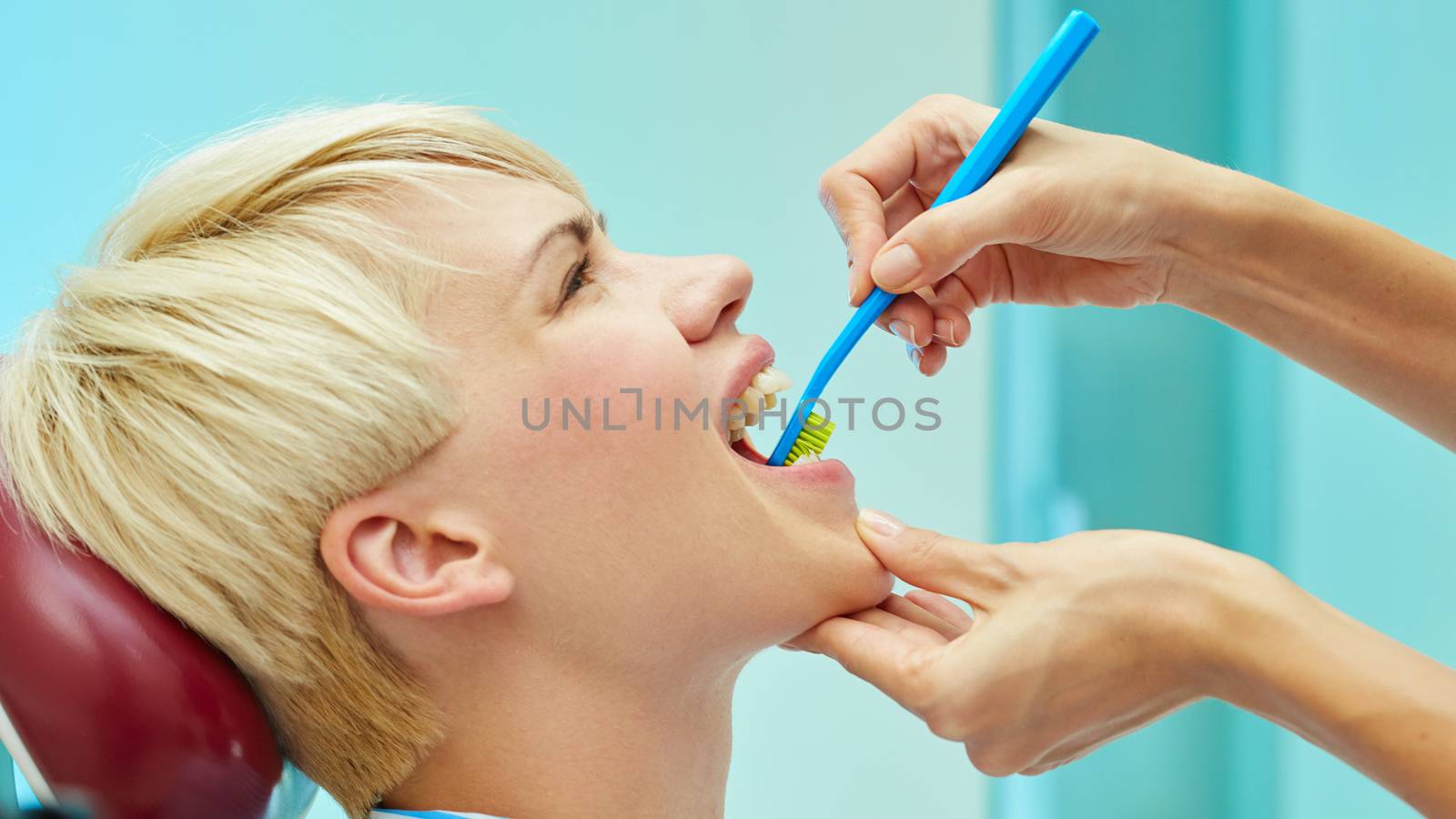 dentist brushing teeth to her patient in dental clinic