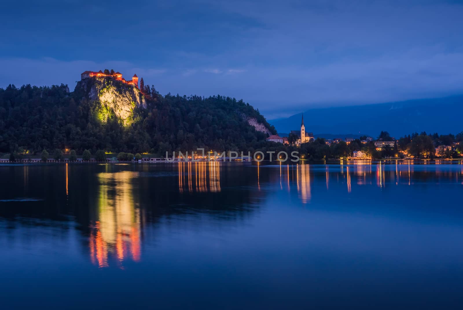 Illuminated Bled Castle at Bled Lake in Slovenia at Night Reflected on Water Surface