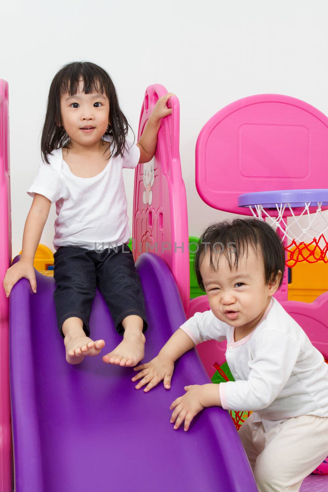Asian Chinese little sister and brother playing on the slide by kiankhoon
