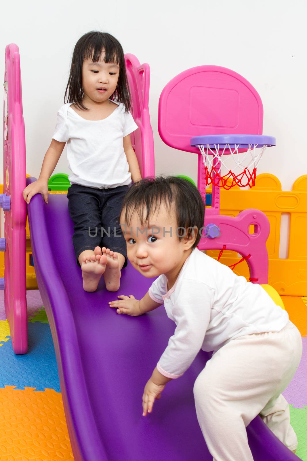 Asian Chinese little sister and brother playing on the slide by kiankhoon