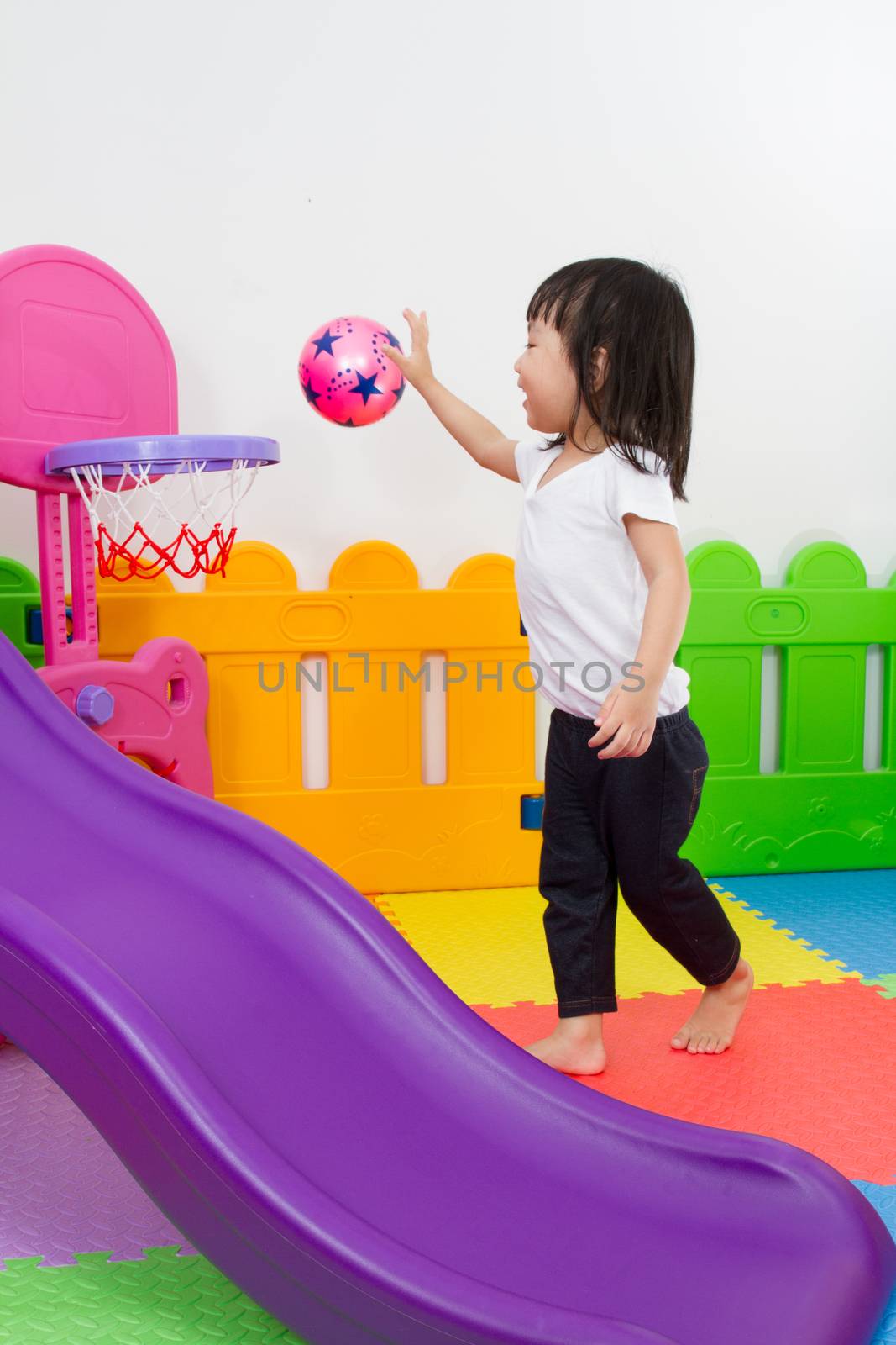 Asian Chinese little girl playing basketball at indoor colourful playground