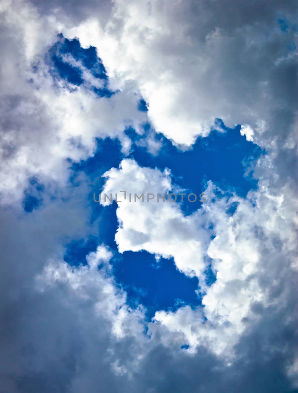 White and dark clouds on blue sky, vertical view