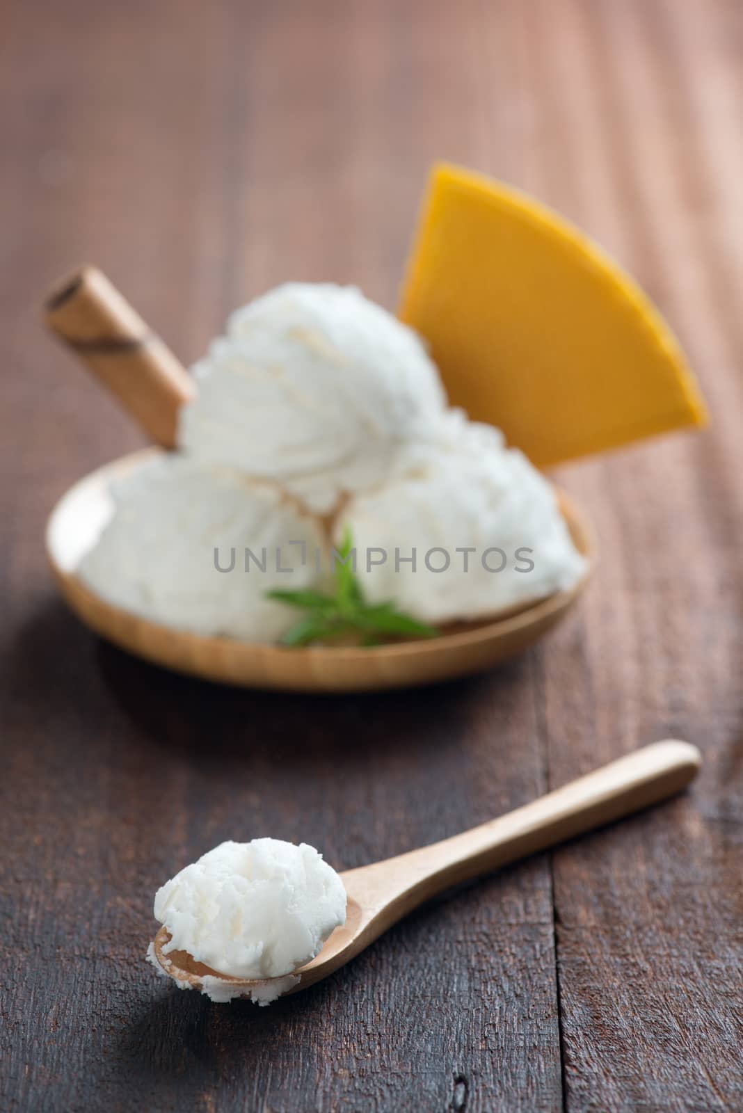 Scoop vanilla ice cream with waffle on wood background. Focus on front spoon.