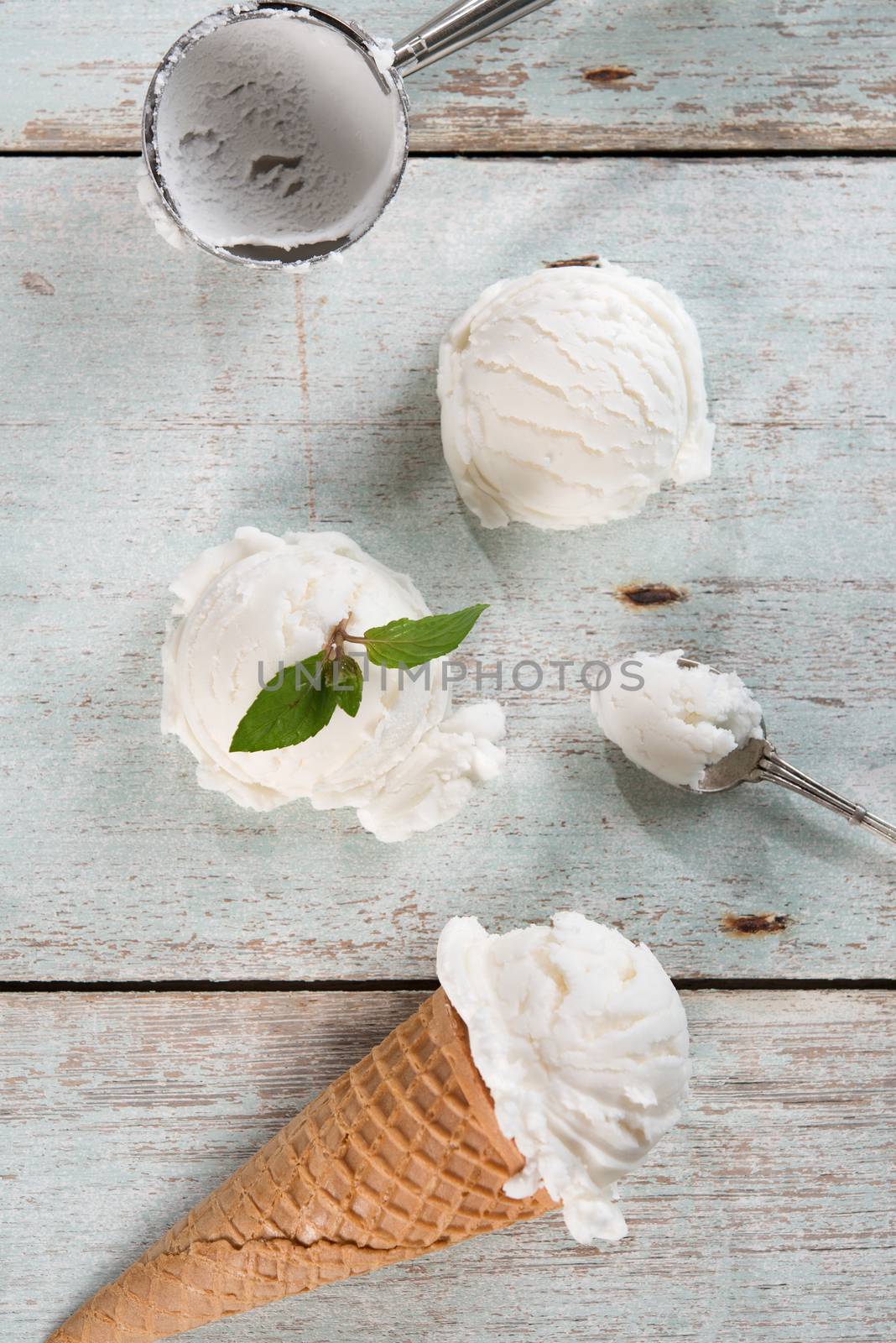 Top view vanilla ice cream in waffle cone with utensil on wood background.
