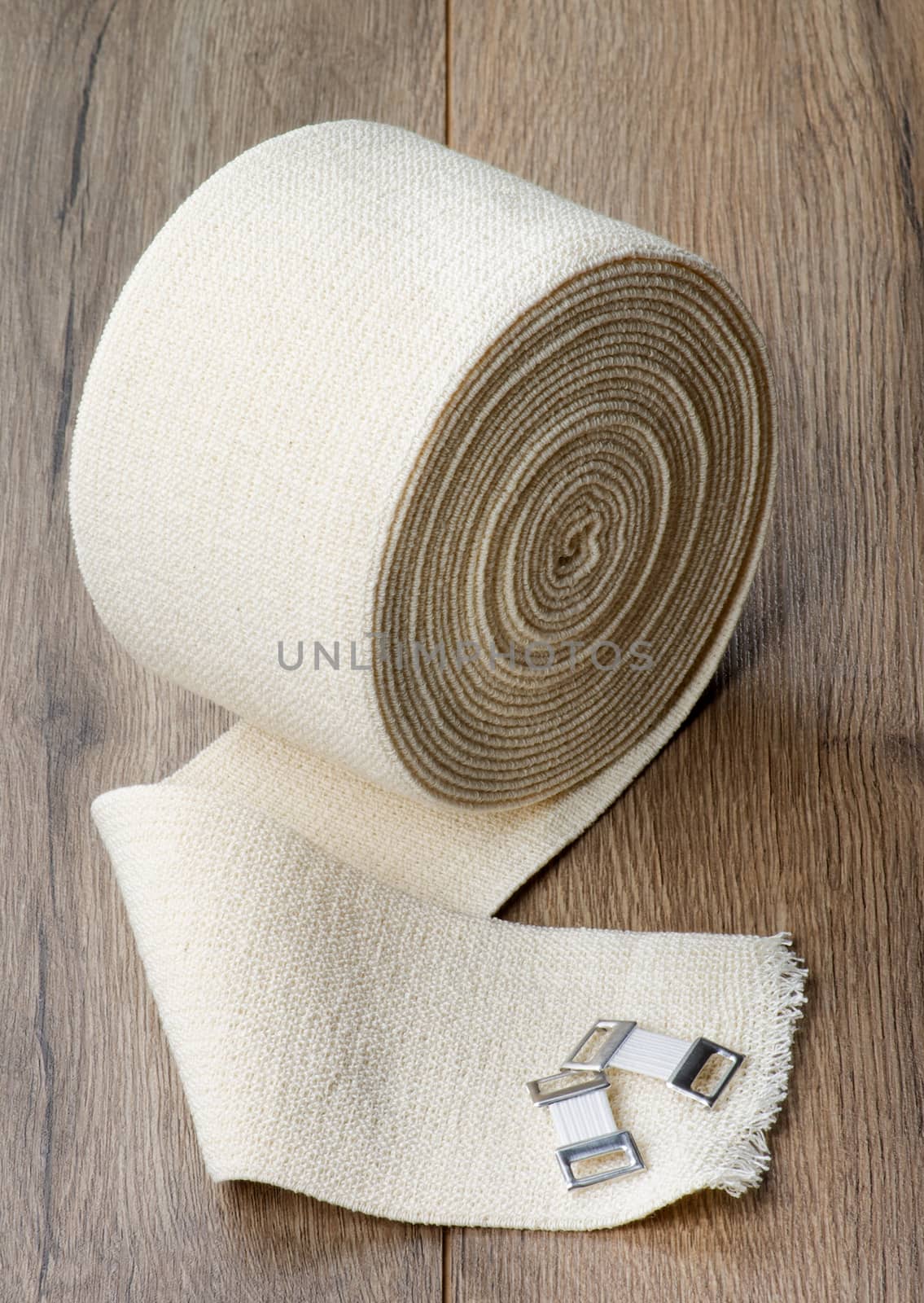 Large Coil of Elastic Bandage with Fasteners closeup on Textured Wooden background