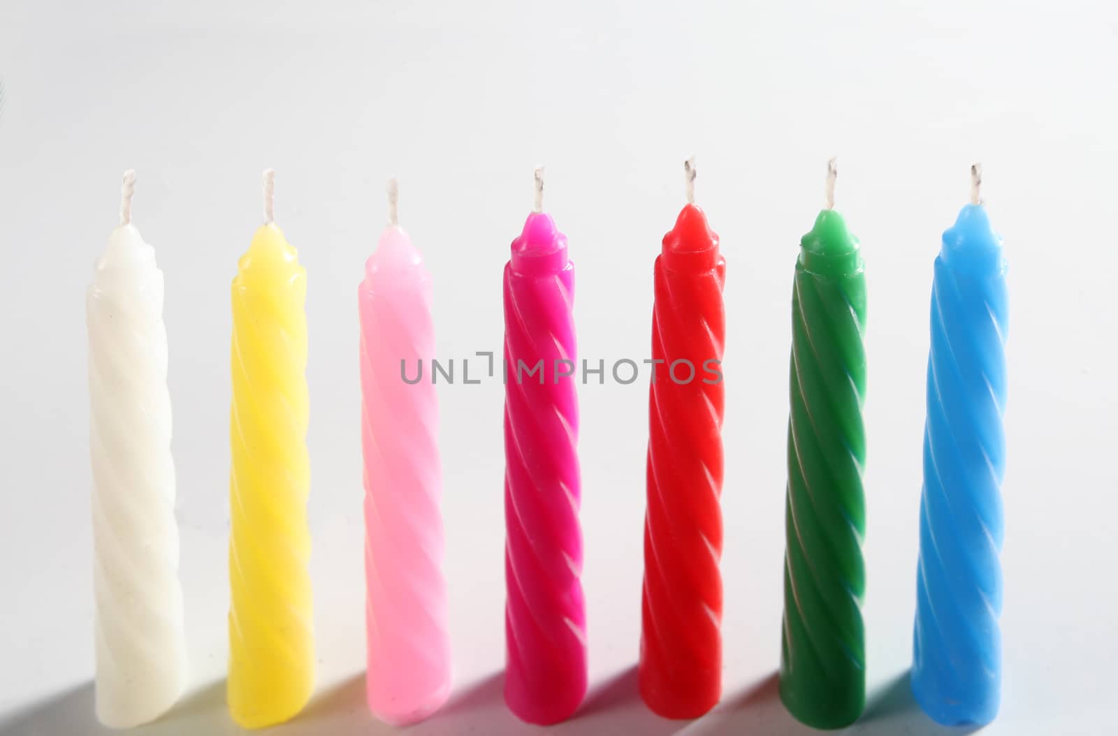 seven colored candles on white background