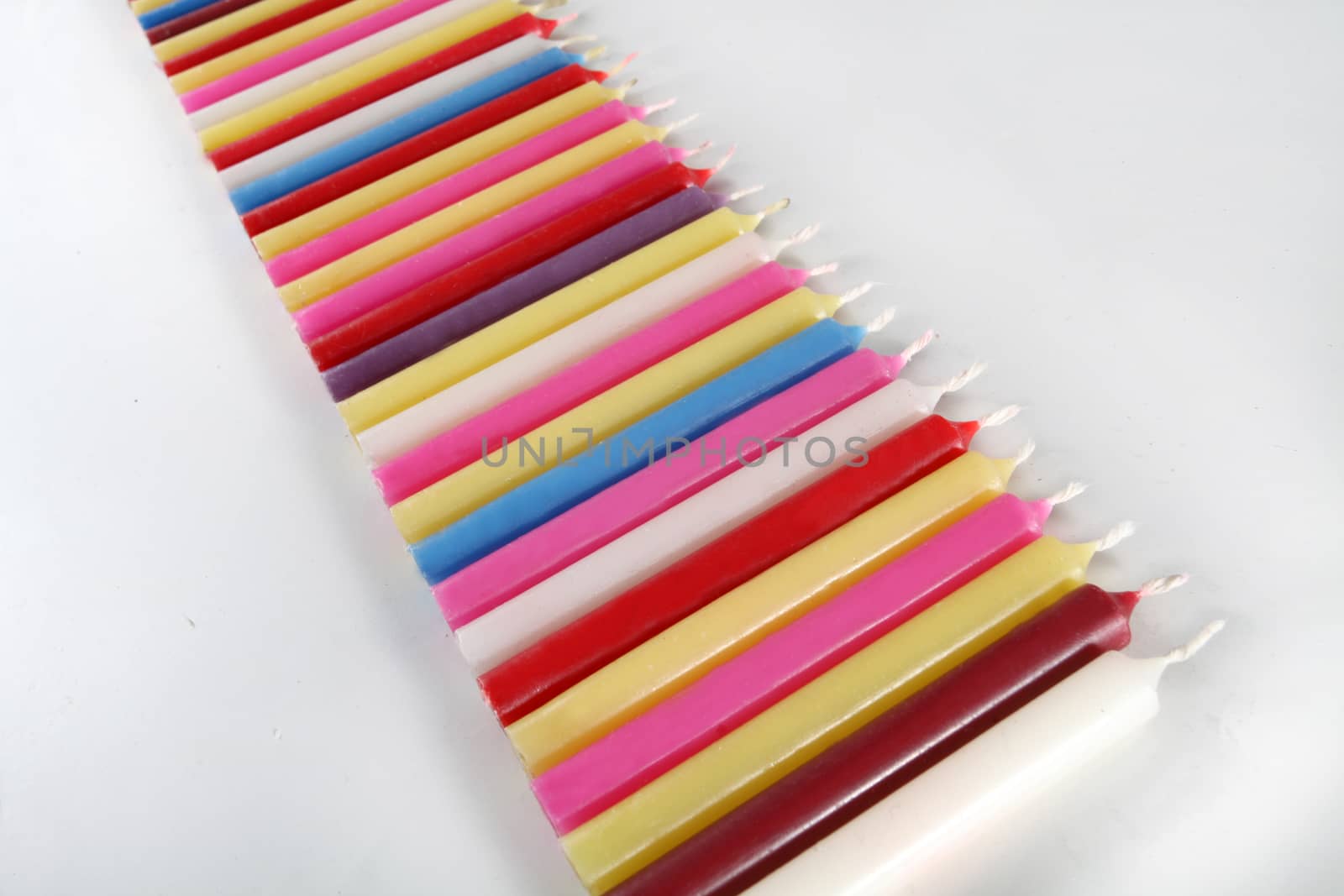 cylindrical candles colored lined on white background