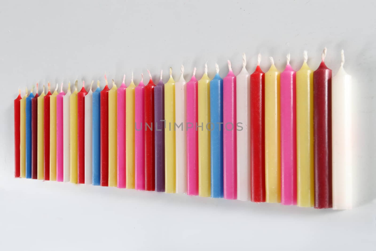 cylindrical candles colored lined on white background