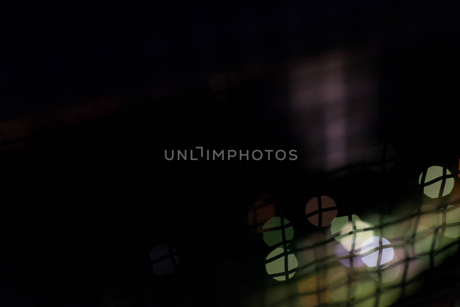 A dark abstract with colored balls of bokeh (out of focus light points) and a wavy wiring in front of them.