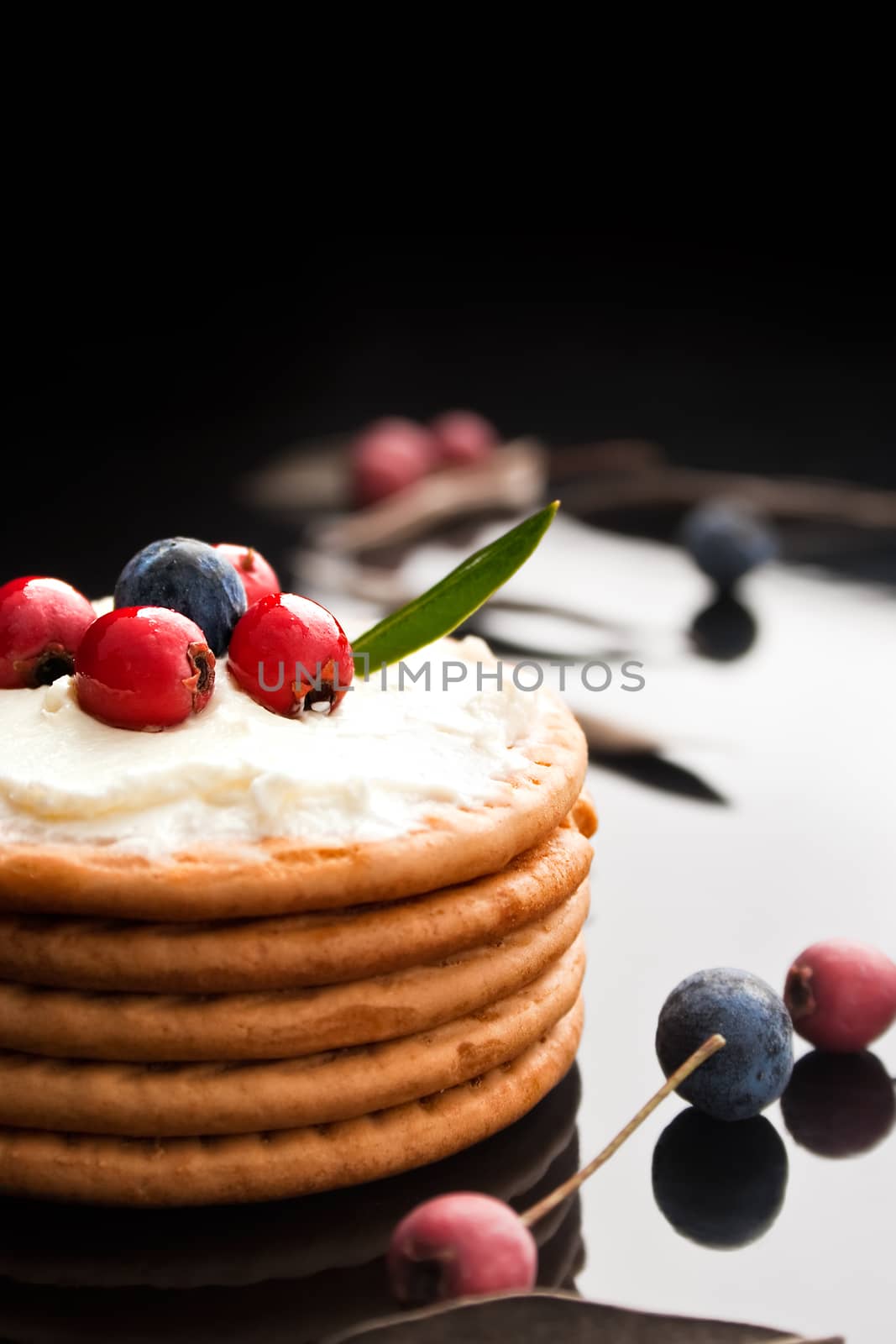  Cookies with cream cheese and blueberries on top surrounded with berries and dry leaves