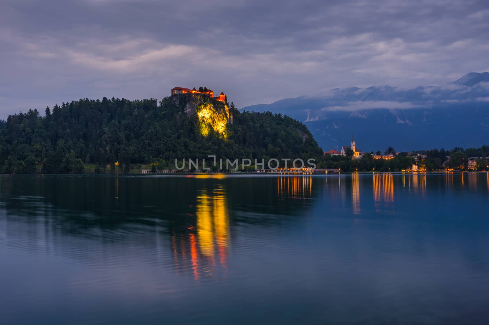 Illuminated Bled Castle at Bled Lake in Slovenia at Night Reflected on Water Surface