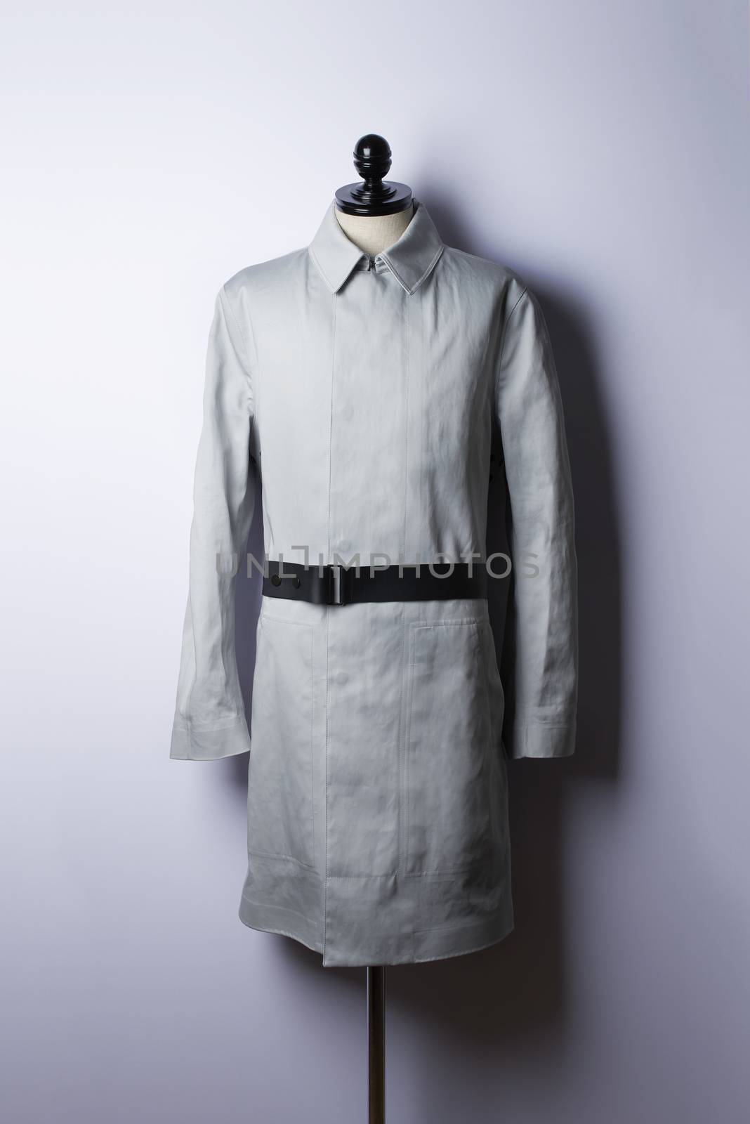beautiful beige trenchcoat with black belt on white wall