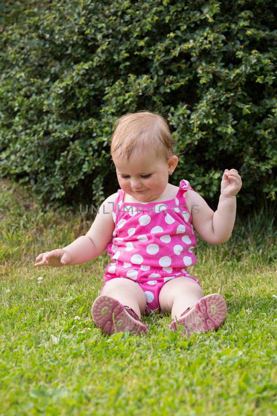 Happy cute little one year old girl outdoor, summer, with pink dress