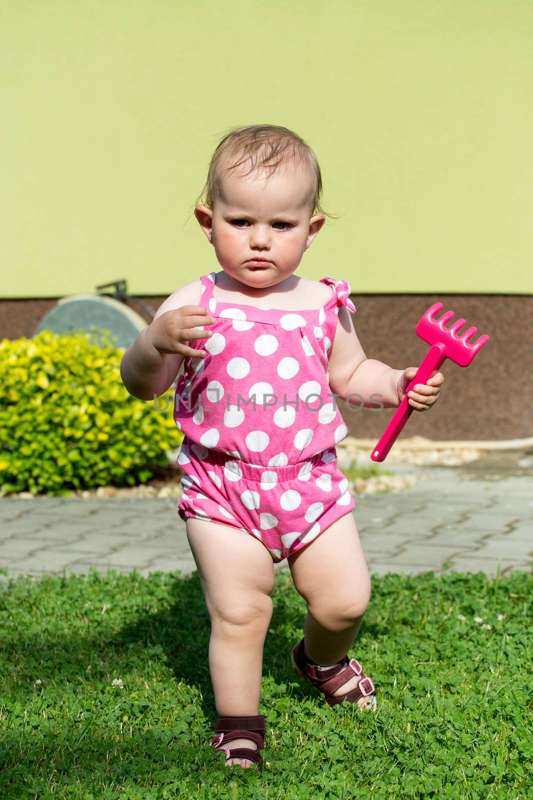 Happy cute little one year old girl outdoor, summer, with pink dress