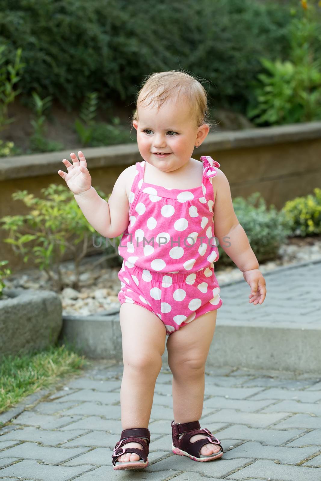 Happy cute little one year old girl outdoor, summer, with pink dress