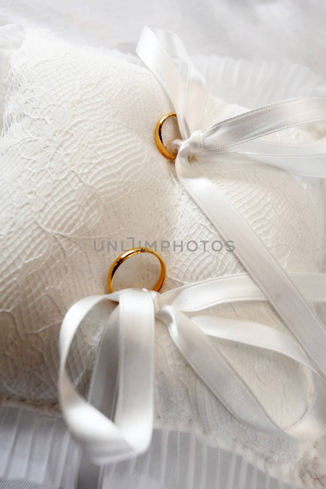 yellow wedding rings on white pillow with tassels