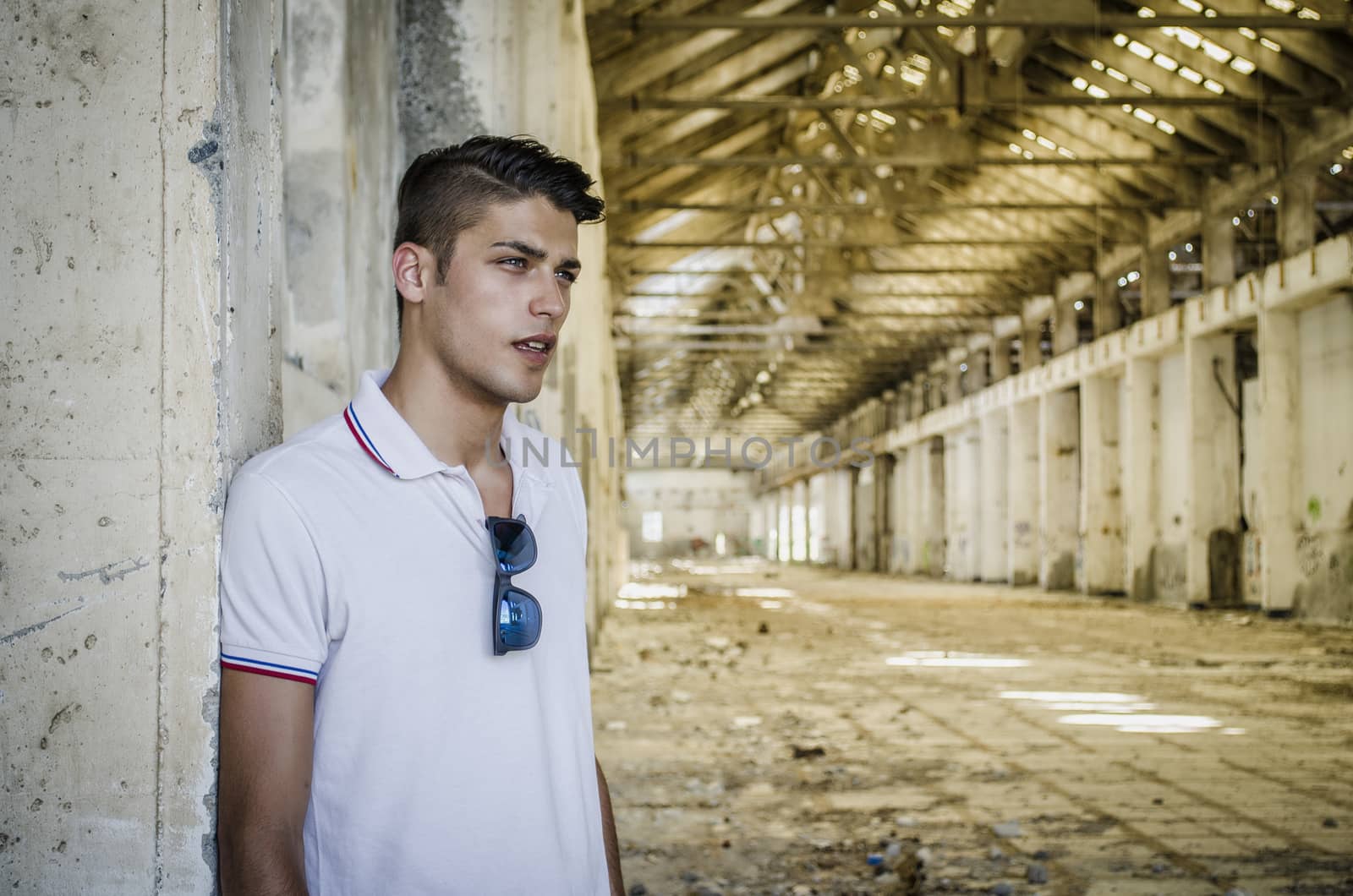 Handsome young man in abandoned, empty warehouse or old factory