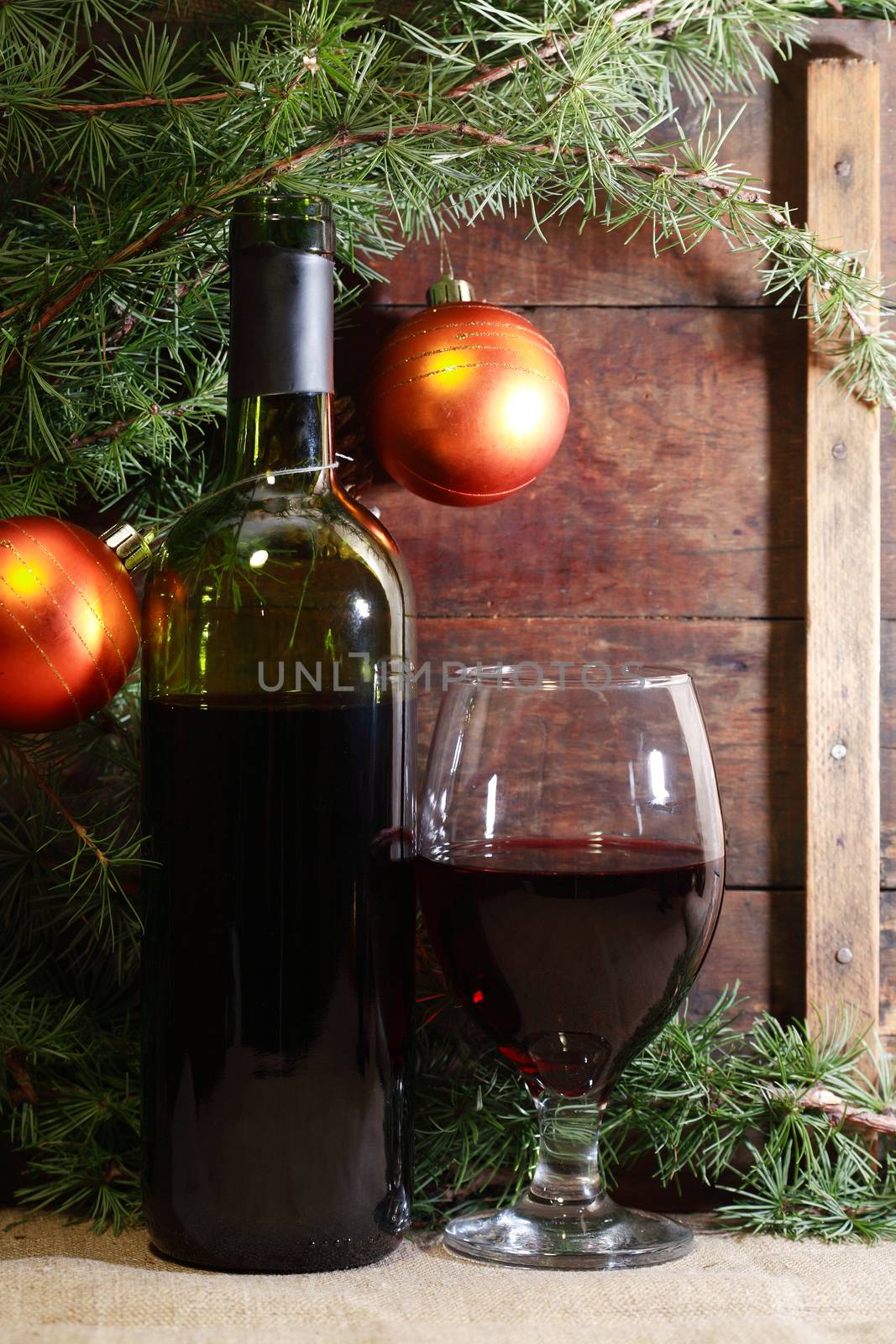 Christmas decoration. Red wine near spruce twigs against old wooden background