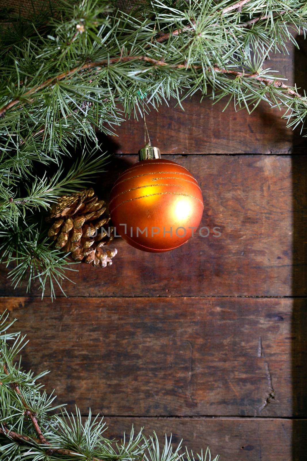 Christmas decoration. Pinecone and glass ball near spruce twigs on old wooden background