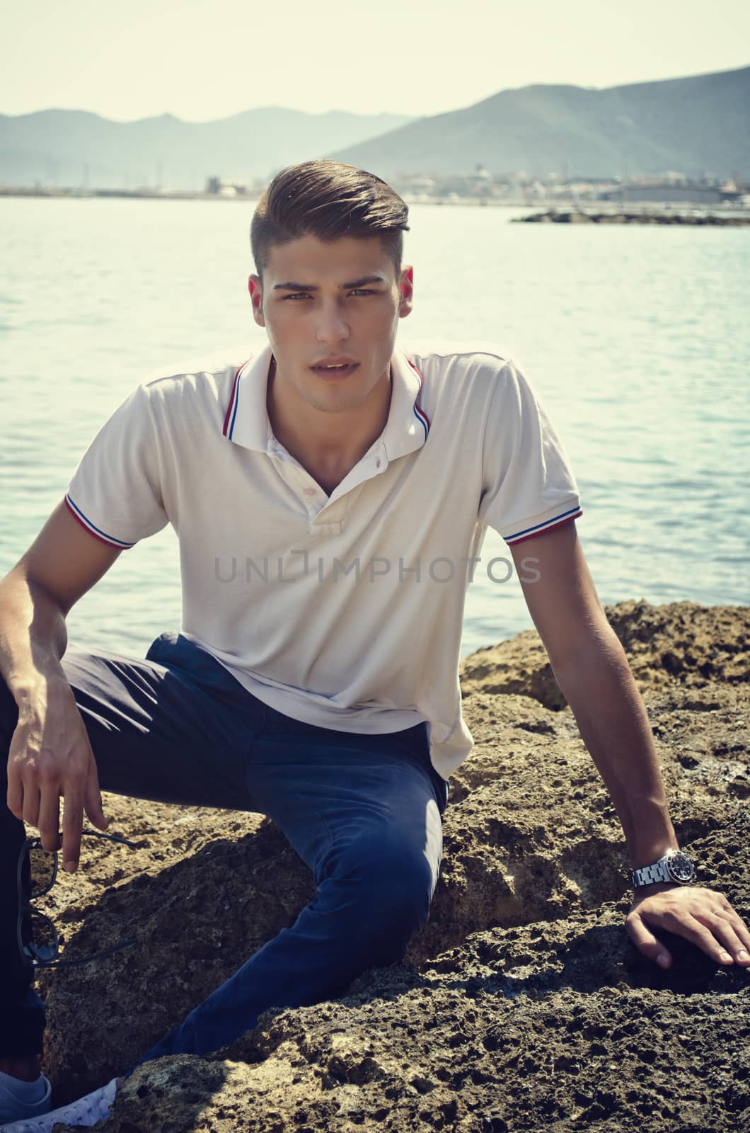 Attractive young man in park resting against tree by artofphoto