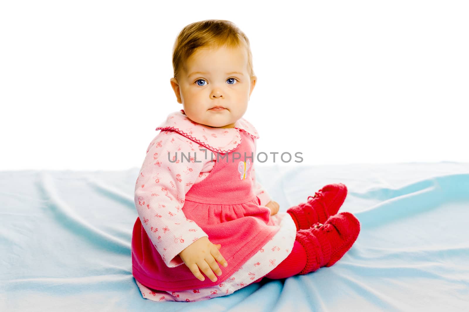 Beautiful baby girl sitting on a blue blanket. Studio