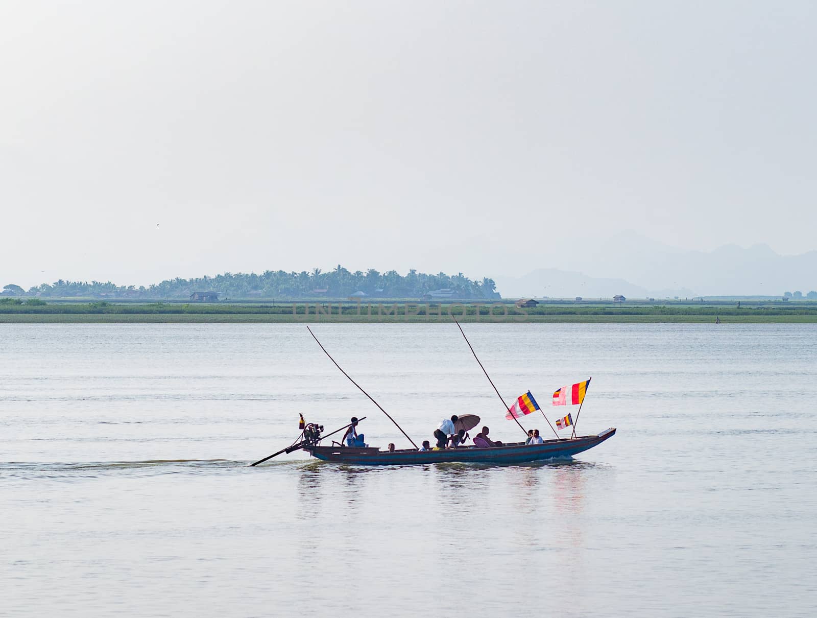 Sittwe, Rakhine State, Myanmar - October 16, 2014: Traditional boat on the Kaladan River at the Rakhine State in Myanmar flying Buddhist flags to demonstrate their religious sympathies.