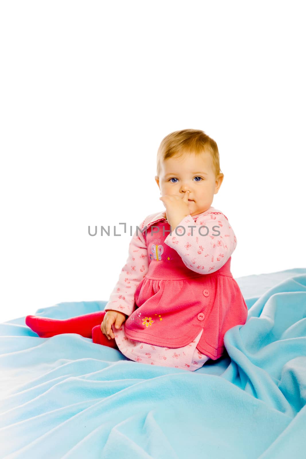 Beautiful baby girl sitting on a blue blanket. Studio