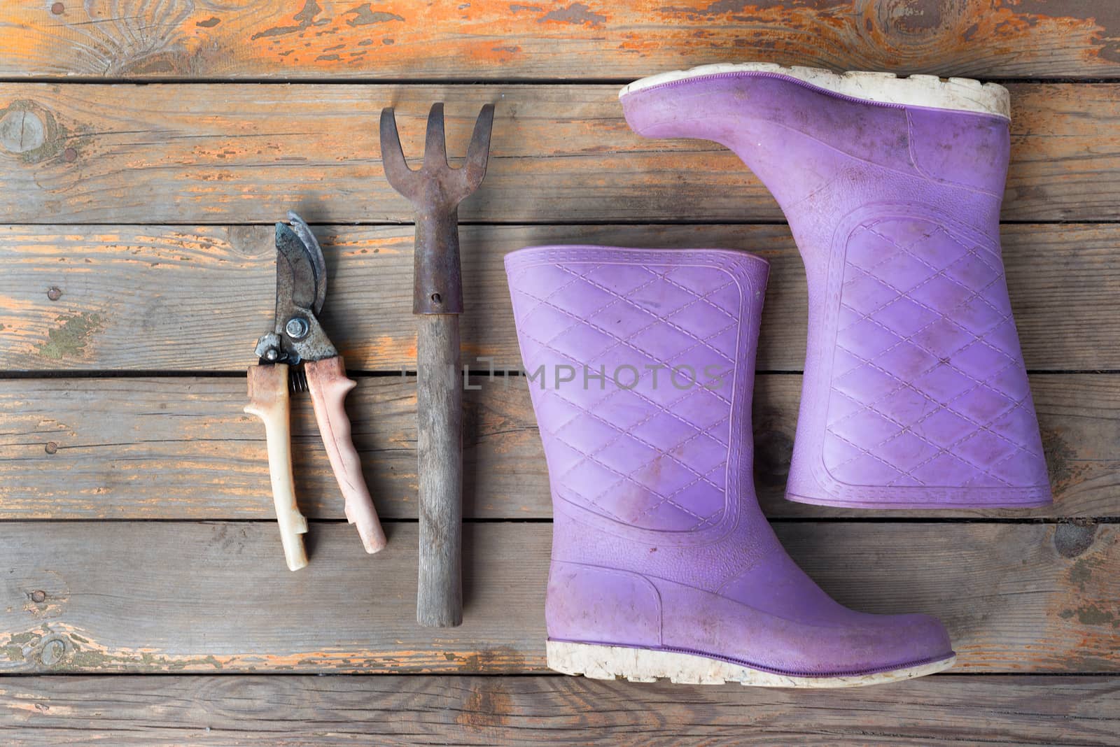 Old wooden texture background with tools and wellingtons, close up view