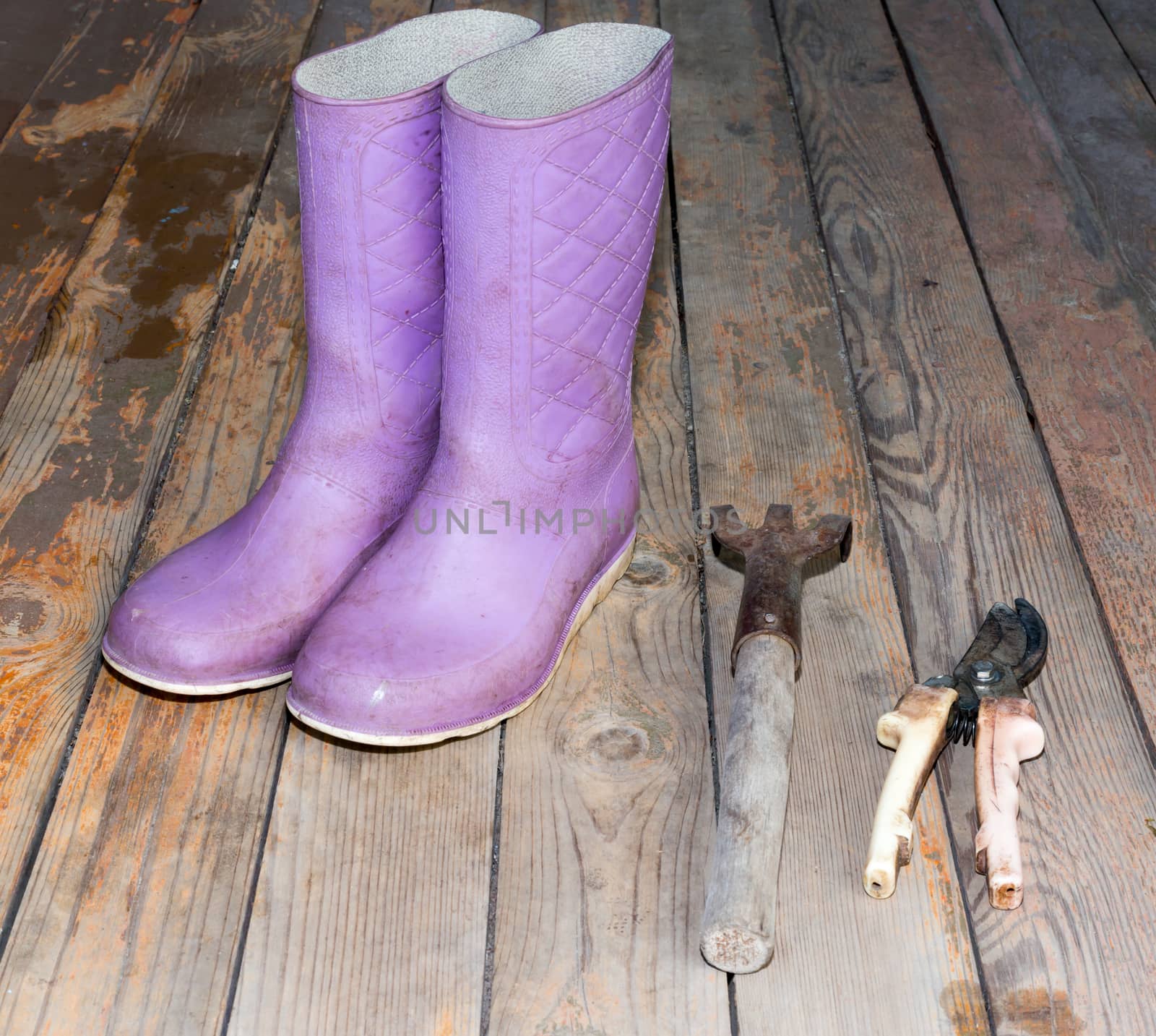 Old wooden texture background with tools and wellingtons, close up view