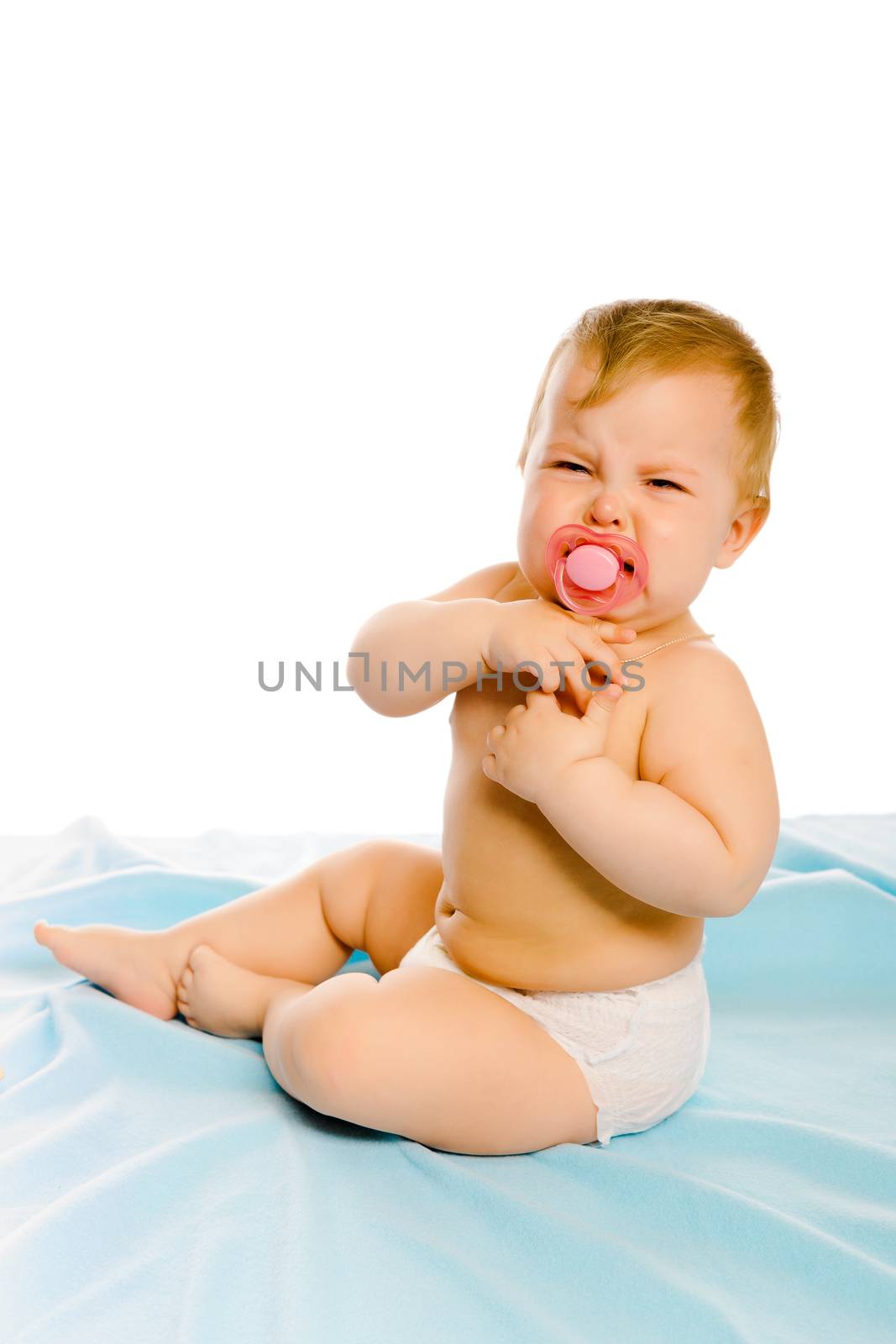 upset baby in diapers on a blue coverlet. Studio