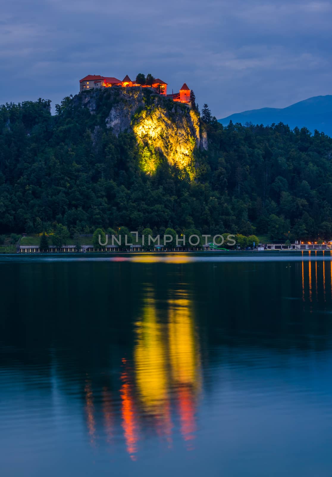 Illuminated Bled Castle at Bled Lake in Slovenia at Night Reflected on Water Surface