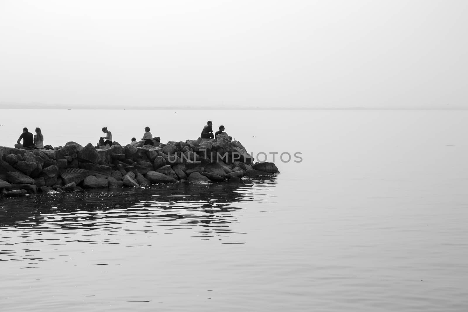 People relaxing on the rocks on the lake by Isaac74