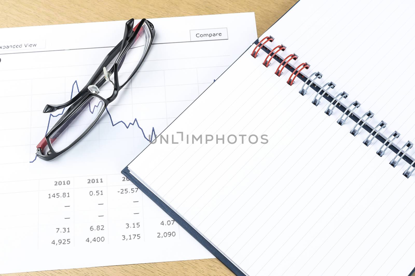 workplace with pen, notebook, glasses and financial report in concept of business and financial 