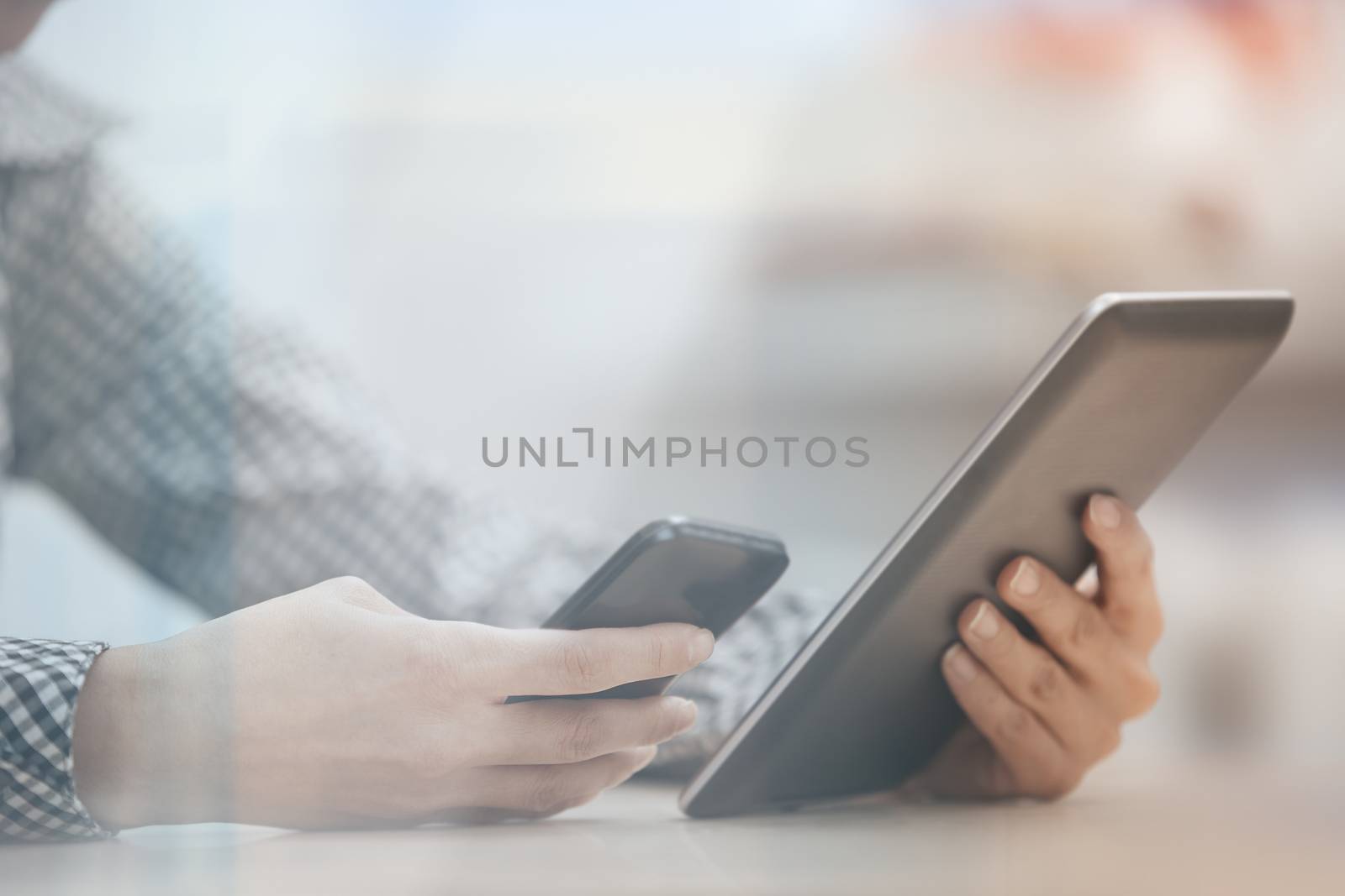 Businesswoman at office working with digital tablet and smartphone beinhd the window