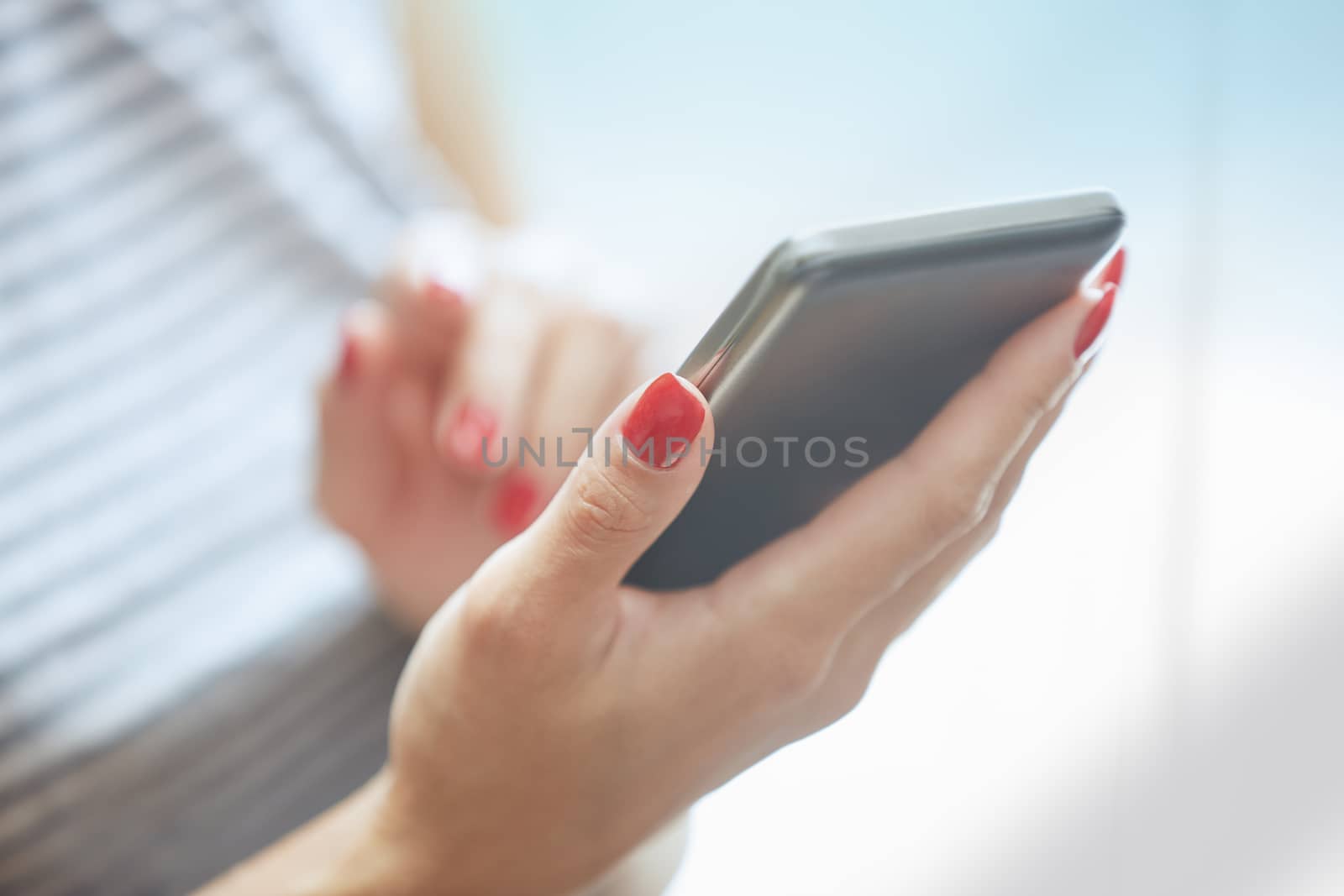 Woman with red manicure using smartphone. Horizontal photo
