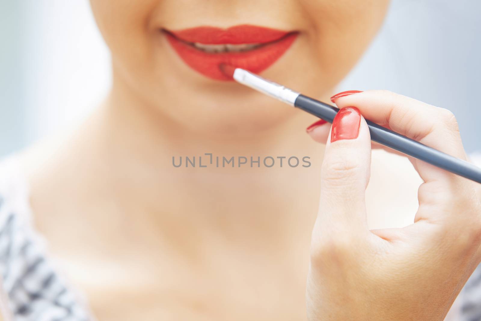 Woman applying red lipstick. Close-up view on face