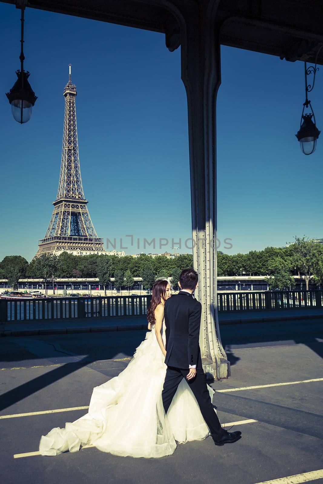 PARIS, FRANCE - JUNE 16: Wedding photography of new married couple on a bridge with Eiffel Tower on background, Paris on June 16, 2015.