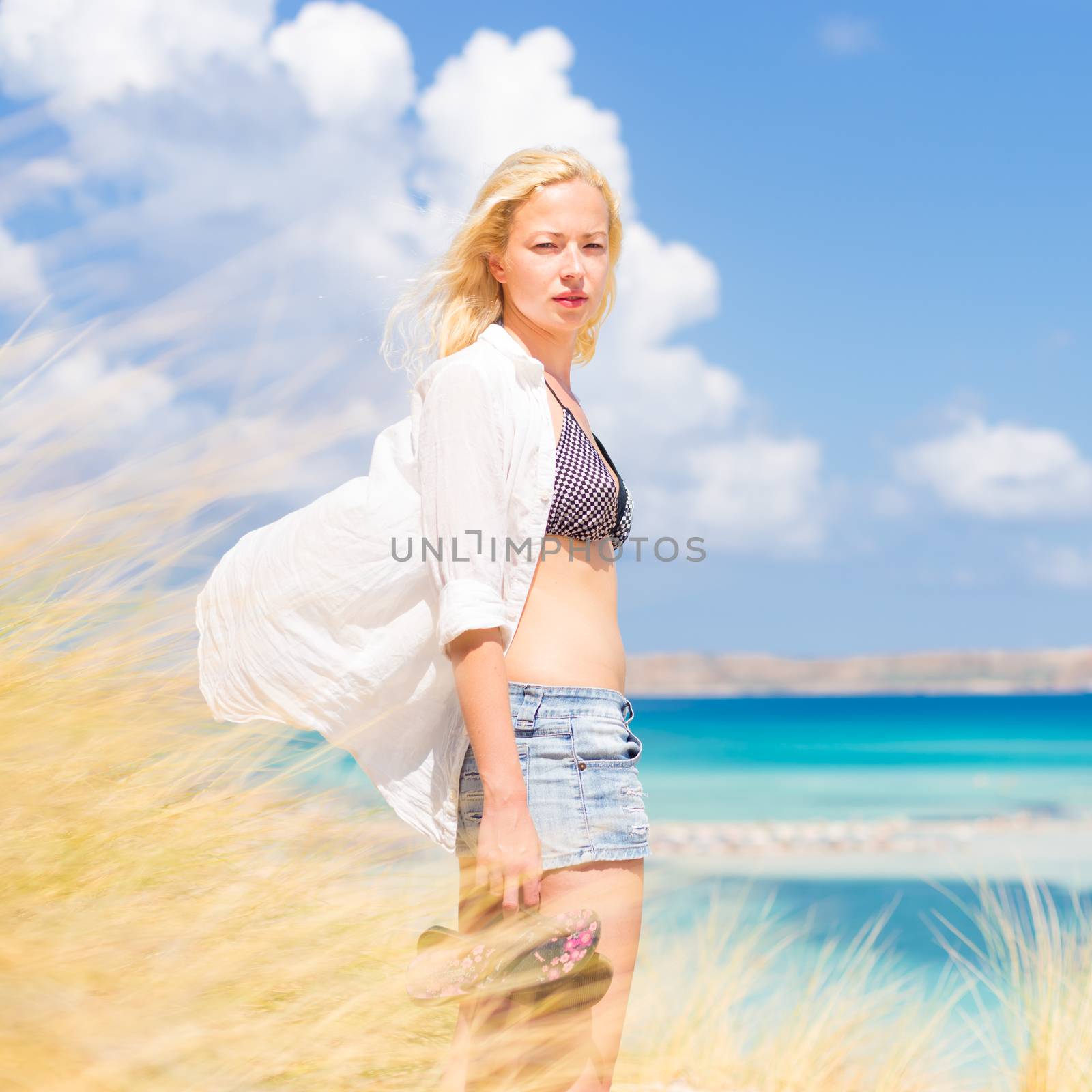 Relaxed woman enjoying freedom and life an a beautiful sandy beach.  Young lady feeling free, relaxed and happy. Concept of freedom, happiness, enjoyment and well being.  Enjoying Sun on Vacations.