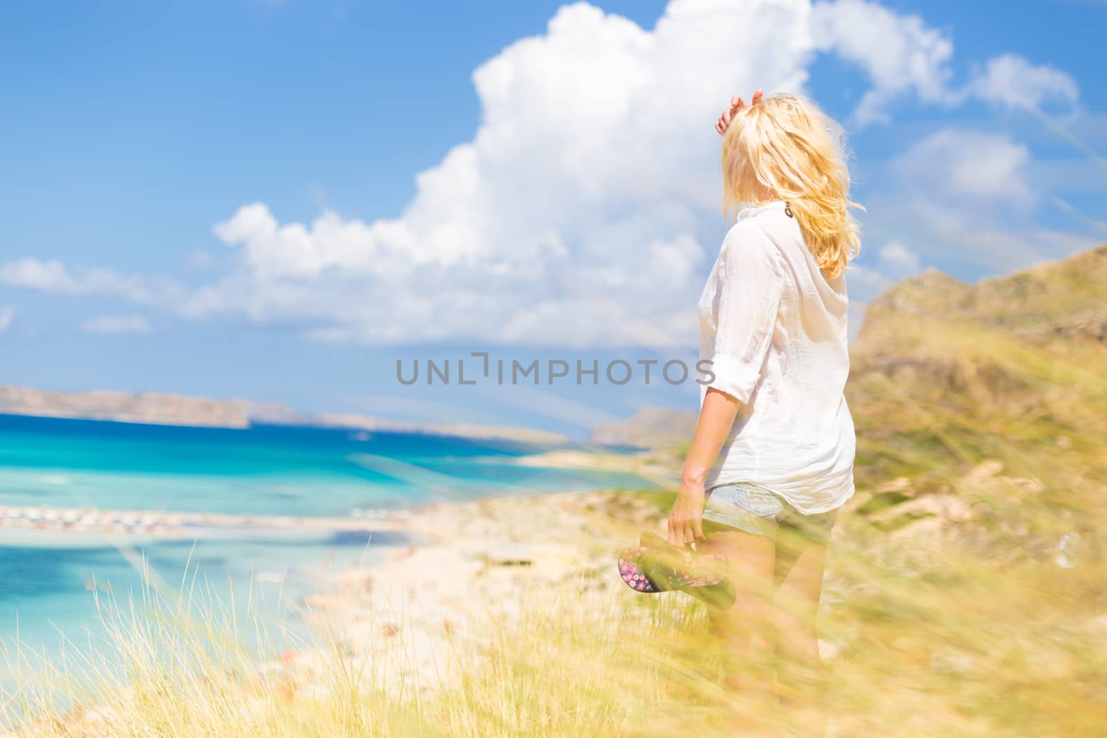 Relaxed woman enjoying freedom and life an a beautiful sandy beach.  Young lady feeling free, relaxed and happy. Concept of freedom, happiness, enjoyment and well being.  Enjoying Sun on Vacations.